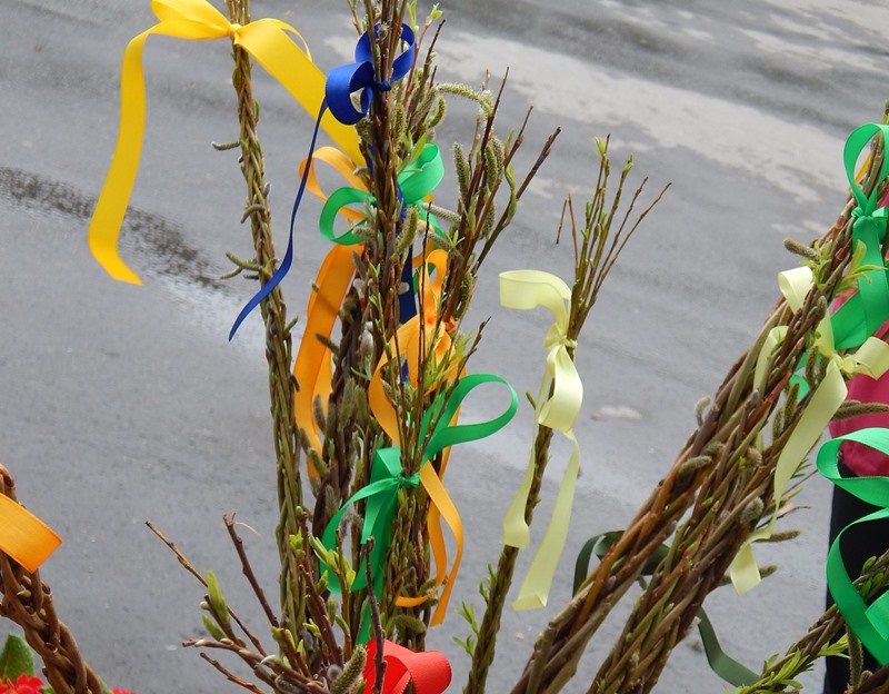 Several Easter whips made from braided willow sticks with colorful ribbons tied at one end, in a bucket, and used at Easter
